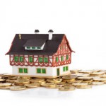Little house on pile of coins. Focus on coins.